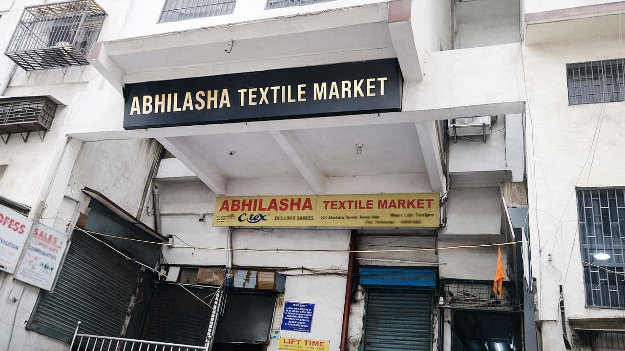 The prominent black and gold signage for "ABHILASHA TEXTILE MARKET" above the entrance of the market in Surat.